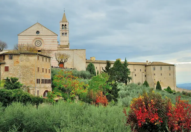 Assisi in autunno con la Basilica di Santa Chiara tra gli alberi colorati
