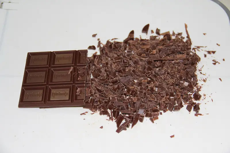Temperaggio a mano del cioccolato fuso su un piano di marmo con una spatola